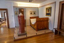 Das Bett ist aus Kirschholz gefertigt udn stammt aus den Jahren zwischen 1820 und 1830. Das ausgestellte Kleid im Empirestil besteht aus Seide. Hergestellt und getragen wurde es zwischen 1820 und 1840. • © ummeteck.de - Silke Schön