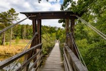 Es handelt sich um eine denkmalgeschützte und an acht Stahlseilen hängende Holzbrücke, welche über einen Nebenarm der Agger führt.  • © ummeteck.de - Silke Schön