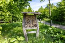 Das Insektenhotel erfreut Bienen & Co. Links daneben steht eine Hütte, an der eine Infotafel angebracht ist.  • © ummeteck.de - Silke Schön