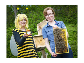 Ida (12; links) mit für die Premiere produzierten Honig und Imkerin Sandra Denker mit einer Bienenwabe aus dem dahinter zu sehenden Schaukasten. // Foto: Anke Hesse